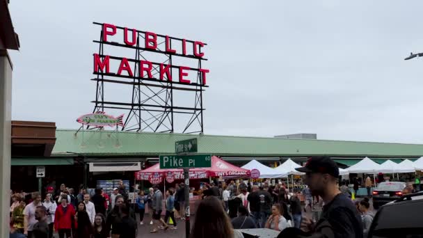 Visitantes y turistas caminan a lo largo del mercado de Seattle Pike Place bajo letrero callejero — Vídeo de stock