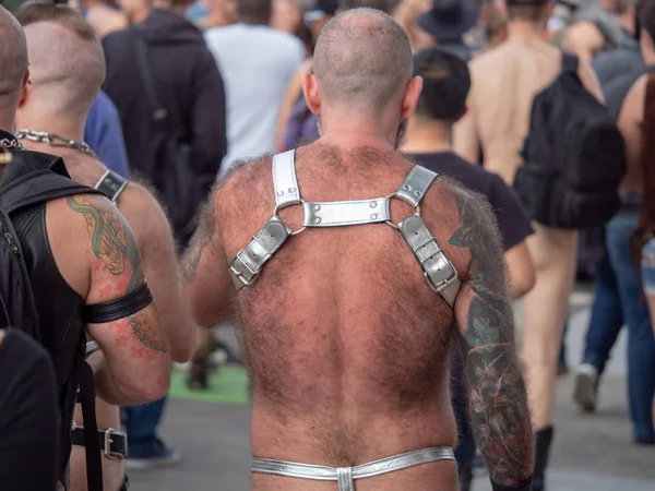 Vista trasera del hombre peludo con arnés BDSM plateado y tanga caminando en multitud — Foto de Stock
