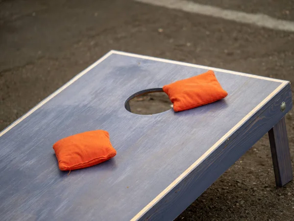 Bolsas de frijoles anaranjados sentadas en plataforma de cornhole azul — Foto de Stock