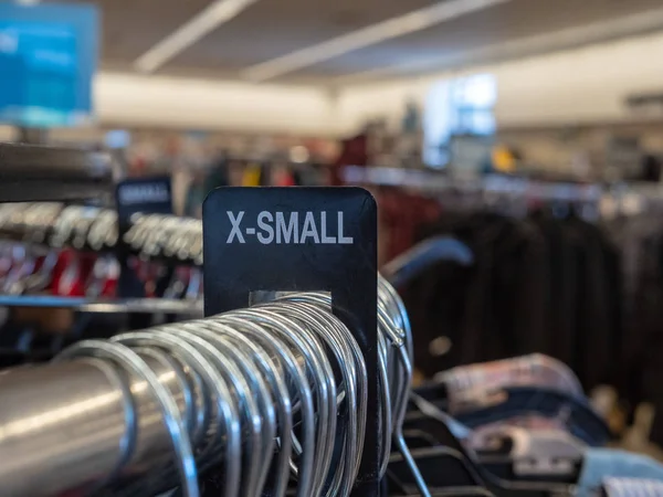 Señal de sección de ropa extra pequeña X-small en estante colgante de acero con perchas en grandes almacenes — Foto de Stock