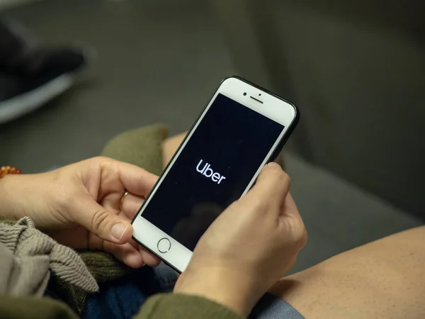 Mujer utiliza la aplicación móvil Uber en el iPhone mientras viaja en tren subterráneo — Foto de Stock