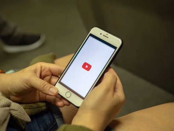 Mujer abriendo aplicación móvil de YouTube con logotipo en la pantalla del iPhone mientras viaja en tren subterráneo — Foto de Stock