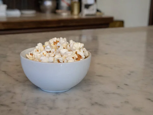 Malá hromada čerstvý popcorn v porcelánové misce na mramorové čítač — Stock fotografie