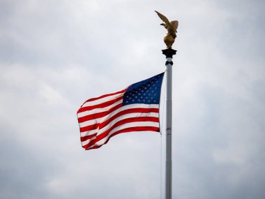 Amerikan bayrağı üzerinde üfleme gün kartal heykeli ile kafasına bulutlu.
