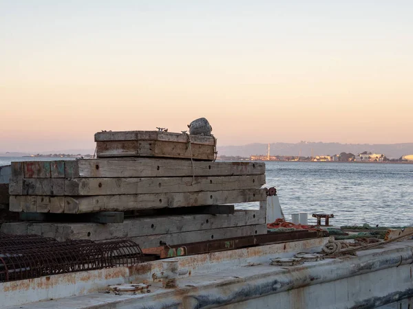 Paletas de madera y materiales de construcción sentados en un buque de carga con vistas a la masa de agua y la costa — Foto de Stock