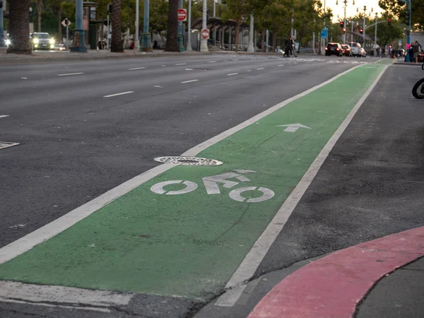 Green dedicated bike lane along city street in evening — Stock Photo, Image
