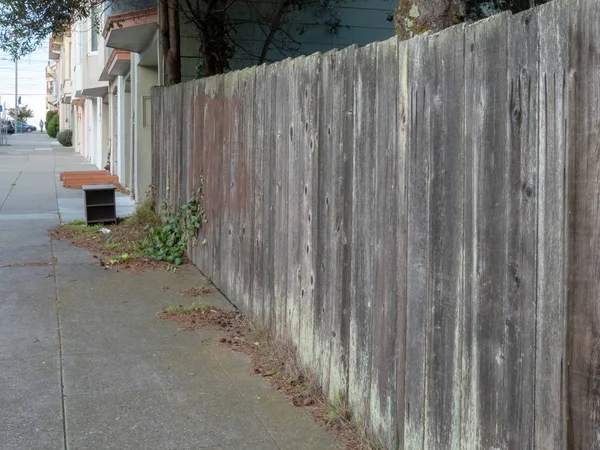 Cerca de madera sin pintar en una tranquila calle de barrio durante el día — Foto de Stock