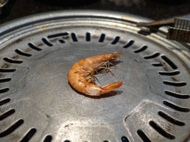 Karanlık restoranda Koreli barbekü ızgarasında oturan yalnız kabuklu karides