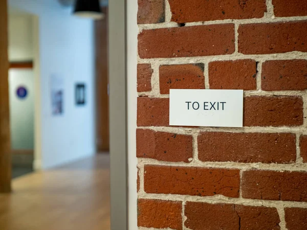 To exit sign on brick wall in a modern warehouse lobby office area