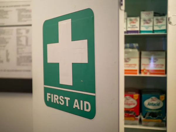 First aid cabinet on an office wall with various pills and medications on inside