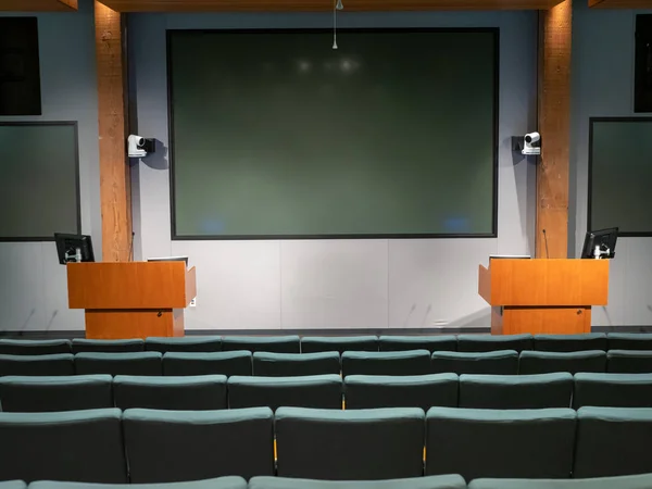 Auditorio de oficina débilmente iluminado con podios dobles y pantallas multiproyector — Foto de Stock