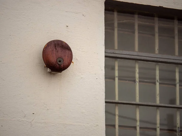 Campana de alarma oxidada colgando fuera de la ventana grande fuera del edificio de la escuela — Foto de Stock