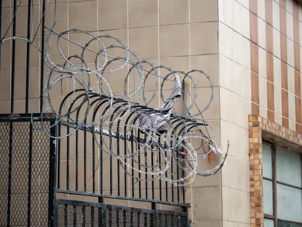 Barbed razor wire over black fence with items stuck inside — Stock Photo, Image