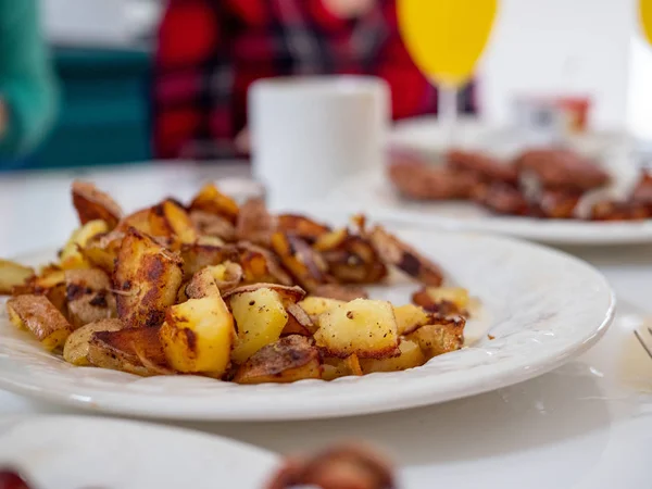 Közeli fel a hagyományos amerikai reggeli tányér burgonya, kolbász, szalonnát egy étkezőasztal teljes reggeli spread — Stock Fotó