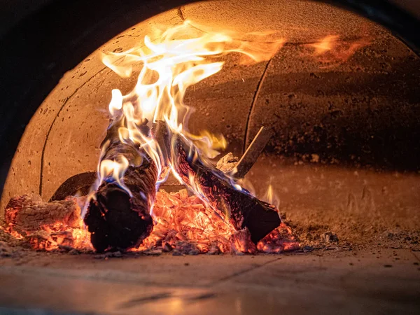 Llamas, troncos, cenizas, brasas dentro de horno de pizza a leña — Foto de Stock