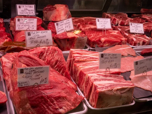 Various cuts of beef and steak behind the glass of a butchers shop in grocery store