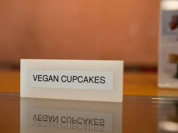 Веганские кексы табличка сидит на столе на прилавке веганской пекарни — стоковое фото