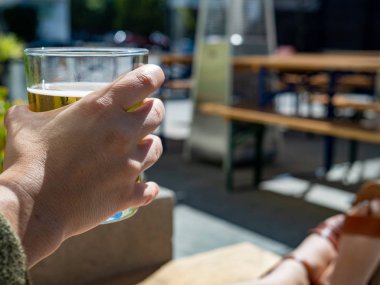 Güneşli bir günde kısa bir bardak soğuk bira tutan kadınlar el