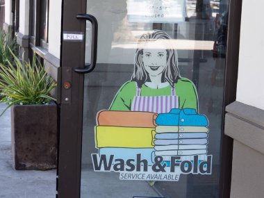 Wash and fold service available sign posted outside laundromat door clipart