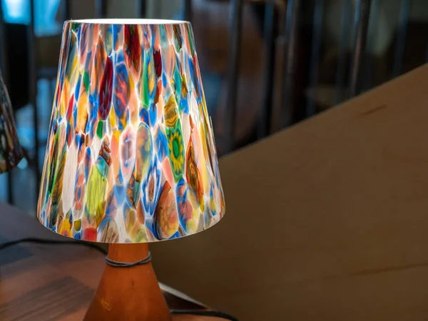 Colorful desk lamp with soft glow sitting on table near railing — Stock Photo, Image