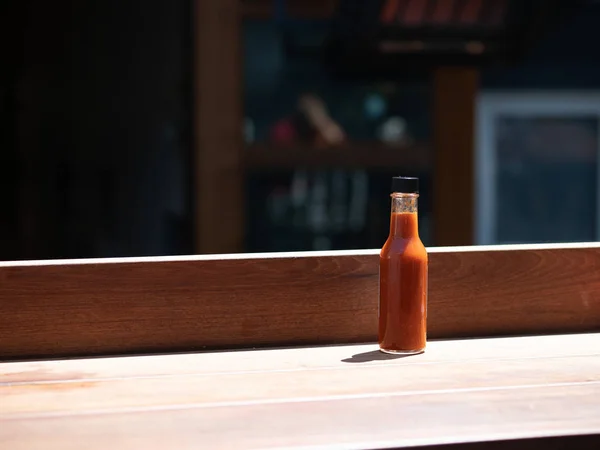Hot sauce bottle sitting on table in outdoor dining area at restaurant