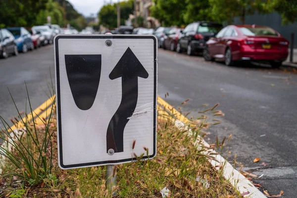 Trafik skylt dirigera bilar att gå till höger om median längs trångt Street — Stockfoto