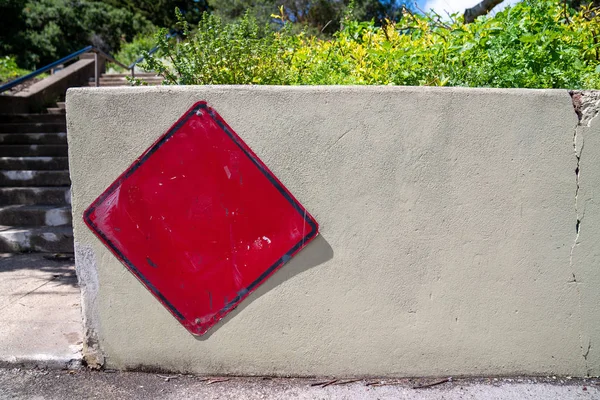 Cartel rojo en blanco sobre barrera de hormigón en día soleado en entorno urbano —  Fotos de Stock