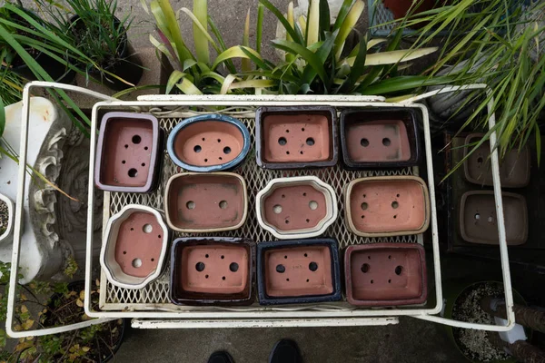Las macetas de varios tamaños en un estante en el vivero al aire libre — Foto de Stock