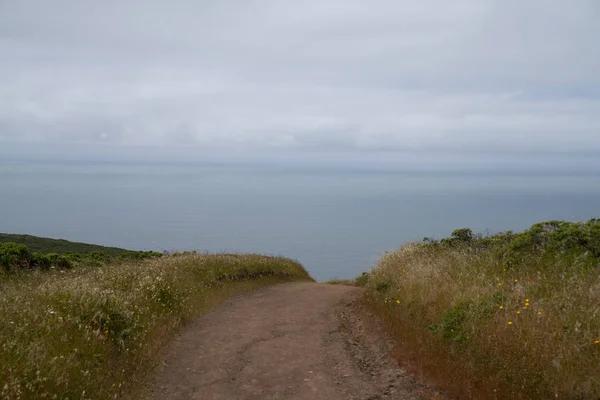 Caminho de terra mergulhando abaixo da vista que conduz à água do oceano, sensação de desconhecido — Fotografia de Stock