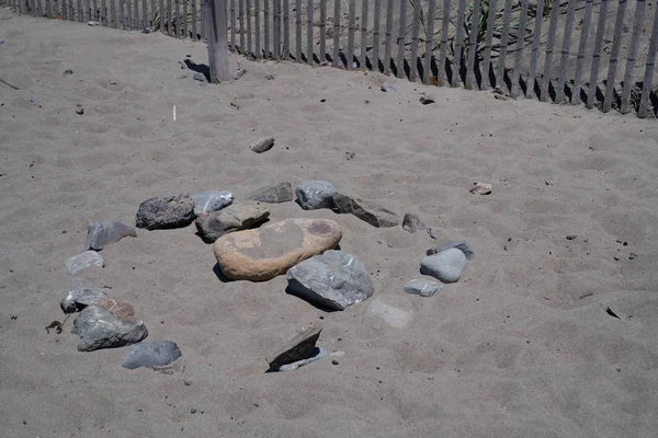 Circular rock formation on beach near fence, tourist and relaxation area