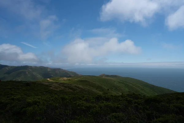 Horizonte verde con ondulantes colinas azules y caminos de tierra y océano — Foto de Stock