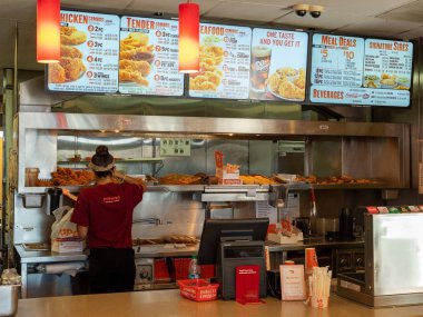 Popeyes Fried Chicken yerde tezgaharkasında ısı lambası tepsisinden tavuk hizmet Veren Kadın