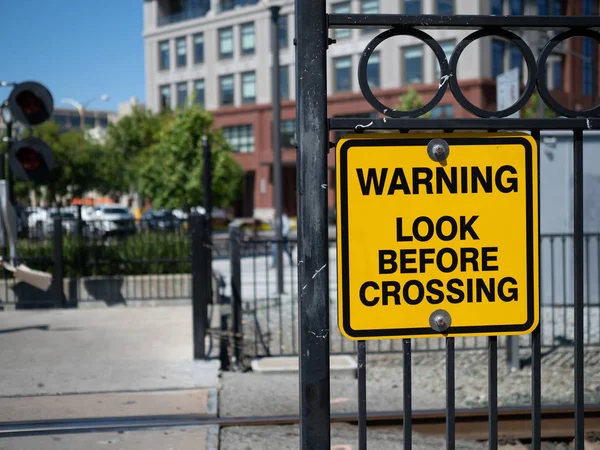 Waarschuwing kijk voor het kruisen van gele waarschuwingsbord bij trein overgang in stad — Stockfoto