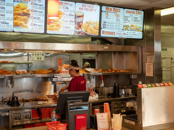 Popeyes Fried Chicken lokasyonunda tezgahın arkasında çalışan kadın