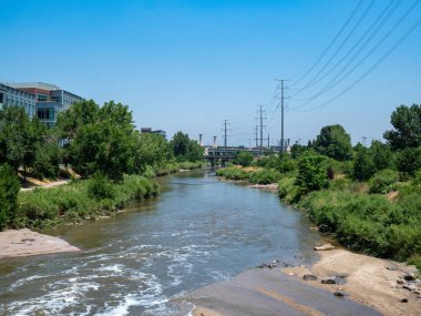 Elektrik hatları ve endüstriyel binalar ile kalabalık bir alanda bir nehir kanalı akışı