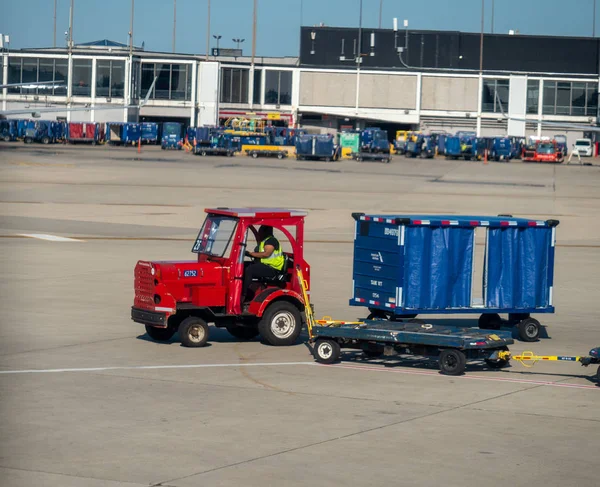 Hombre conduce camión de equipaje en la pista del aeropuerto cerca de la terminal — Foto de Stock