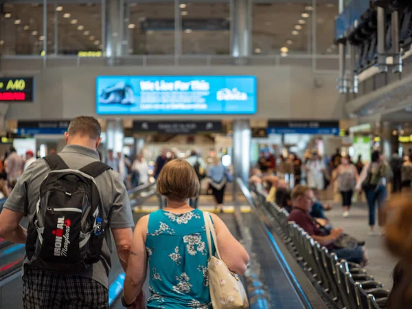 Hombre y mujer de pie en la pasarela en movimiento una terminal del aeropuerto ocupado — Foto de Stock