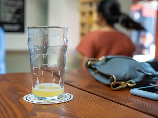 Färdig öl på bordet bredvid kvinnans handväska och telefon — Stockfoto