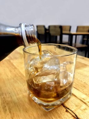Cam buz, buz küpleriyle bir cam için cam şişe içki üzerinden boşalırcasına cola Cola cola cam içecek içecekler Restoran masada buz.