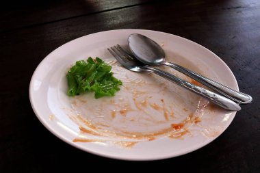 plaka boş çöp yiyecek ve bir tabak pilav, tabak çatal ve kaşık yeşil sebze yaprakları