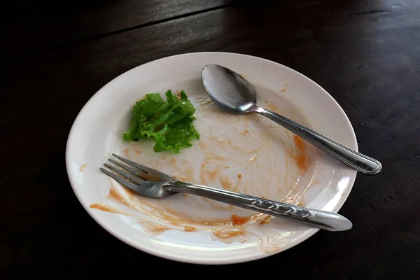 ごみ箱を空の料理とご飯 プレートのフォークとスプーンの皿の上の緑の野菜の葉をプレートします — ストック写真