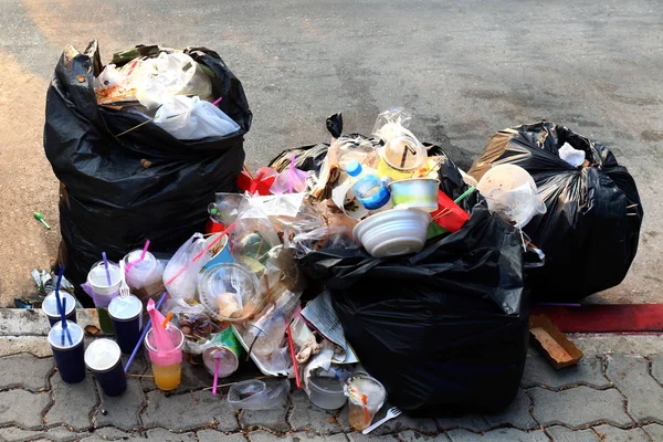 Pile of Garbage plastic black and trash bag waste many on the footpath, pollution trash, Plastic Waste and Bag Foam tray Garbage many on floor, Waste plastic