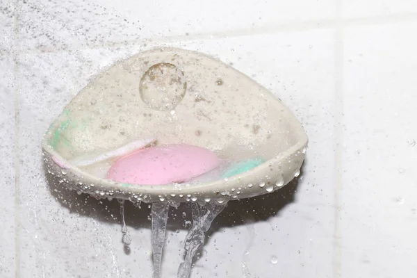 soap, water splash and soap bar on dish at wall, soap cubes used (selective focus)