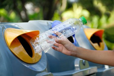Çöp kutusuna, çöp kutusuna, çöp kutusuna, plastik şişeye, geri dönüşüm çöpüne ve ayrımcılık konseptine atmak için çocuğun elindeki plastik atık şişesi.