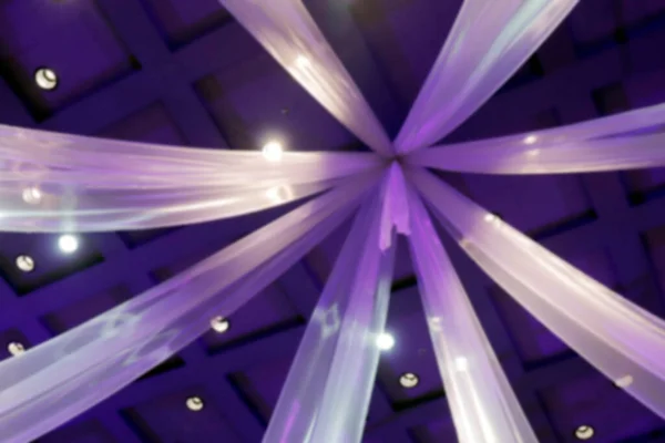 blurred hanging curtains purple color in wedding hall room, decorative curtains on the ceiling interior hall in night