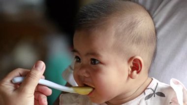 feeding a newborn baby, close-up face portrait, infant smiling and laughing happily, a cute baby thai, asia kid, little baby, asian family lifestyle