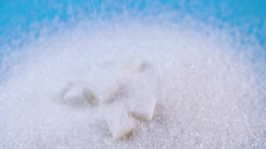 şeker ve beyaz granüllü şeker dökülmesi, aşırı şeker tüketimini, şeker hastalığını ve sağlık risklerini, sağlık farkındalığını, şekerli gıdalar için granüllü şekeri, tatlı içeriğini sembolize eder.