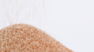 brown sugar, crystals granulated organic sugar pouring onto pile, symbolizing excessive sugar consumption, diabetes and health risks, health awareness, sugar for sweetness food, ingredient dessert