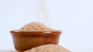 brown sugar in ceramic bowl, crystals granulated sugar pouring onto bowl, symbolizing excessive sugar consumption, diabetes and health risks, health awareness, sweetness food, ingredient dessert