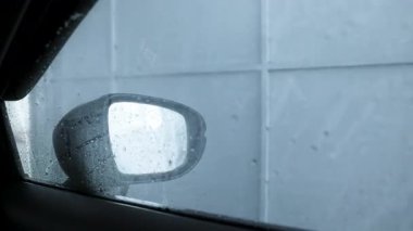 car wash, inside car view during automatic car wash tunnel, with water spray on window, water and foam flowing on car window, representing auto care, cleaning, and car service